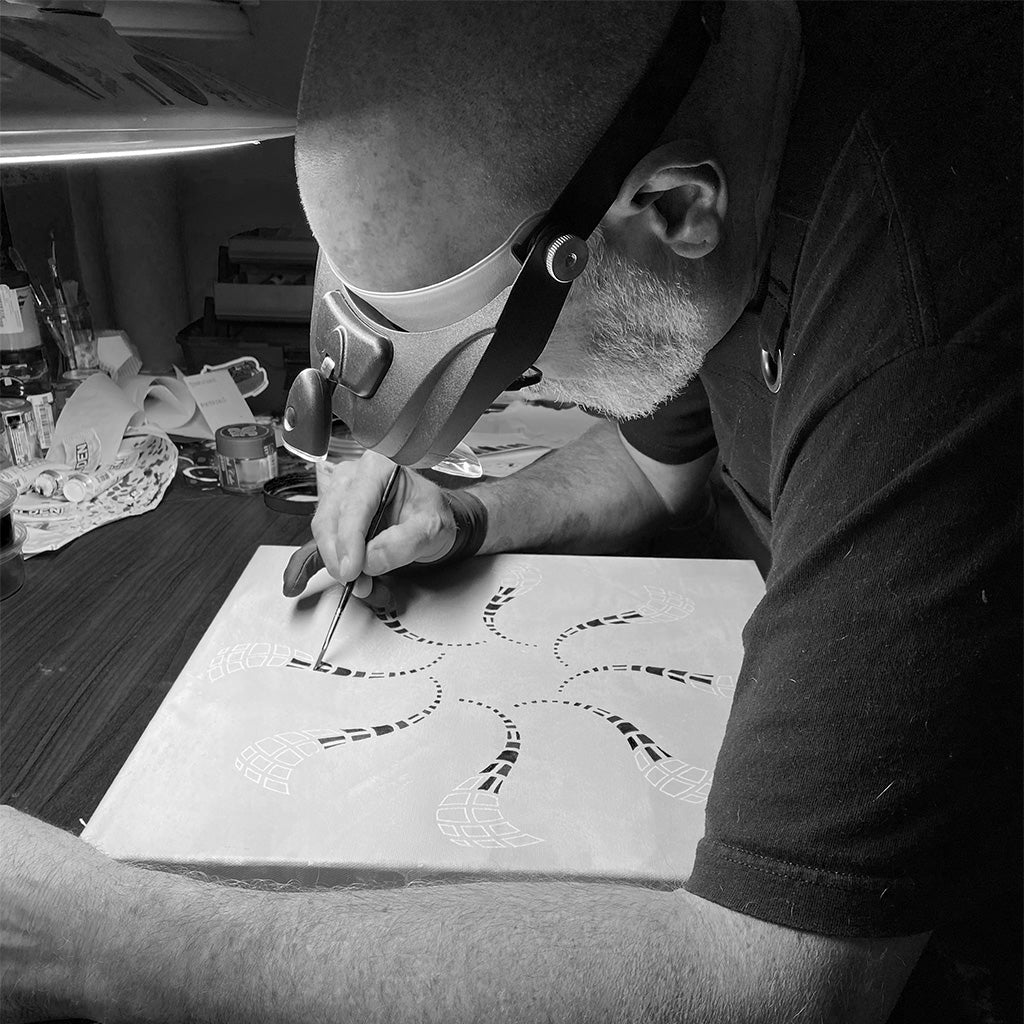 Black and white close-up photo of Scott Hampton painting fine details on a painting.