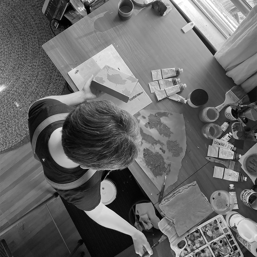 Overhead shot of Monica Hampton painting at her studio desk