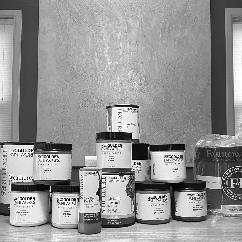 An artfully arranged stack of paint containers, featuring specialty products such as glass beads and weathered granite. Products featured include Golden Paintworks and Farrow & Ball.